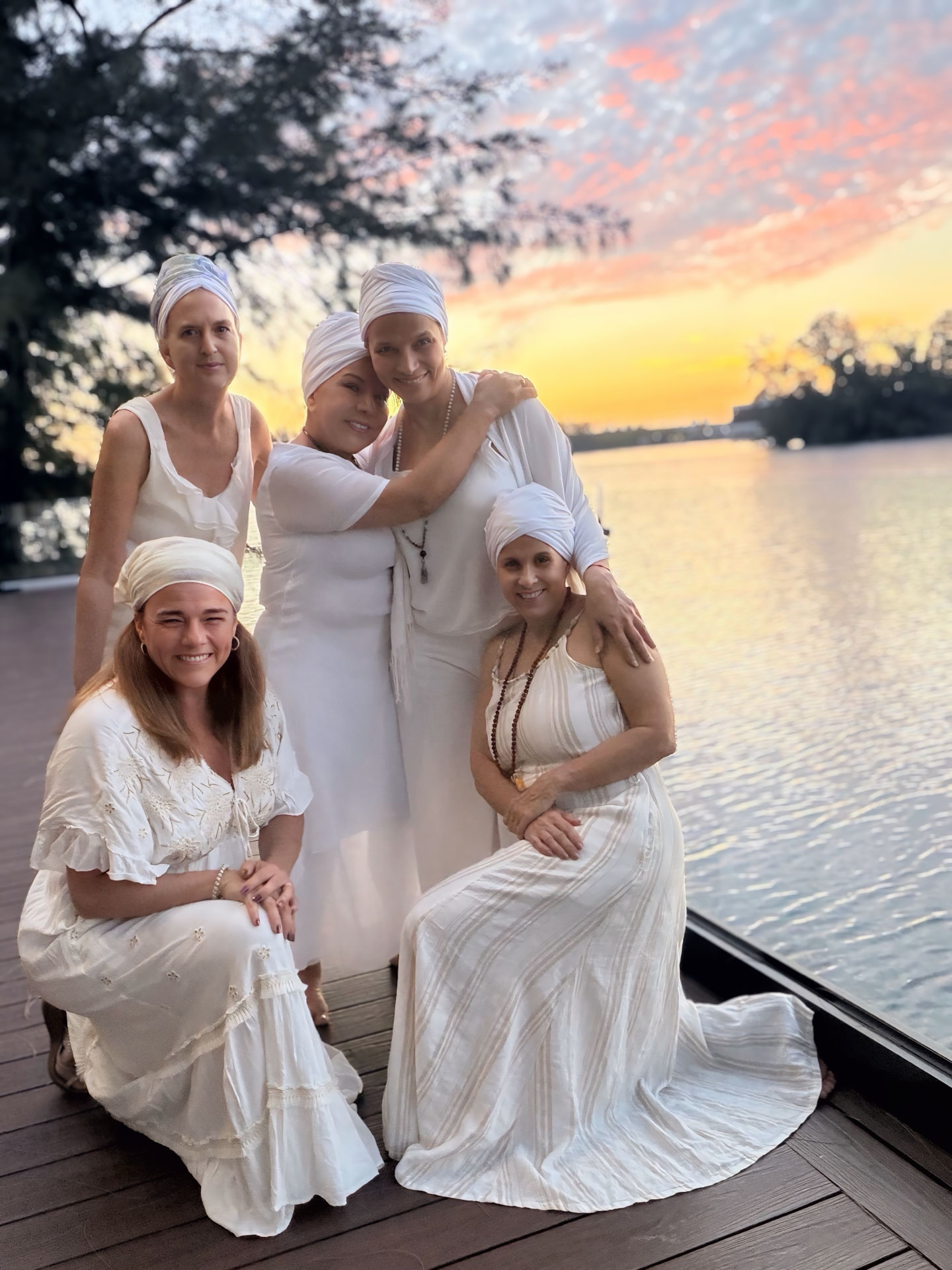 Diana and her training classmates in white attire gathered on a deck by the water at sunset
