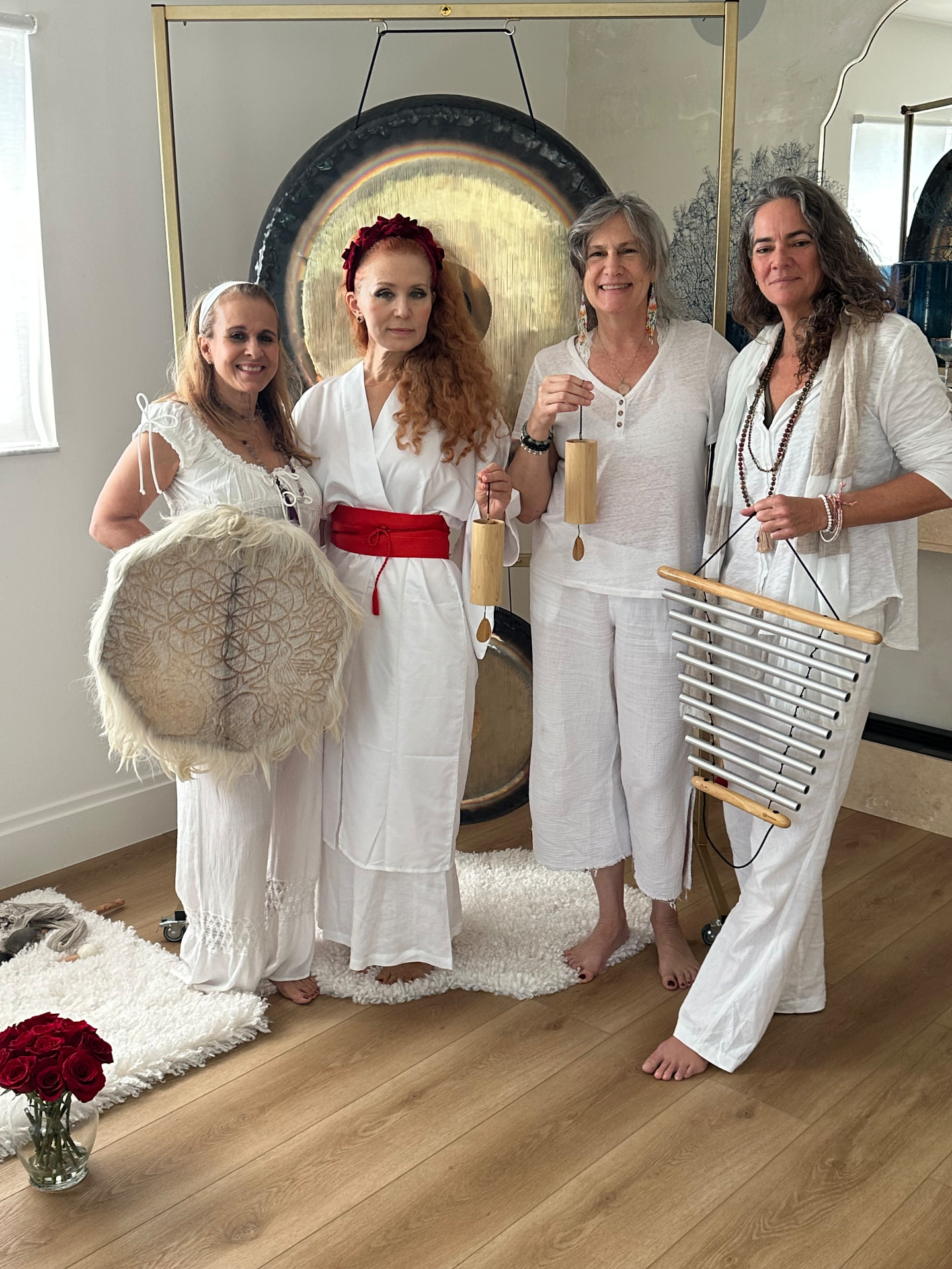 Diana and classmates holding a frame drum, gong, chimes, and a bar chime beside the gong stand